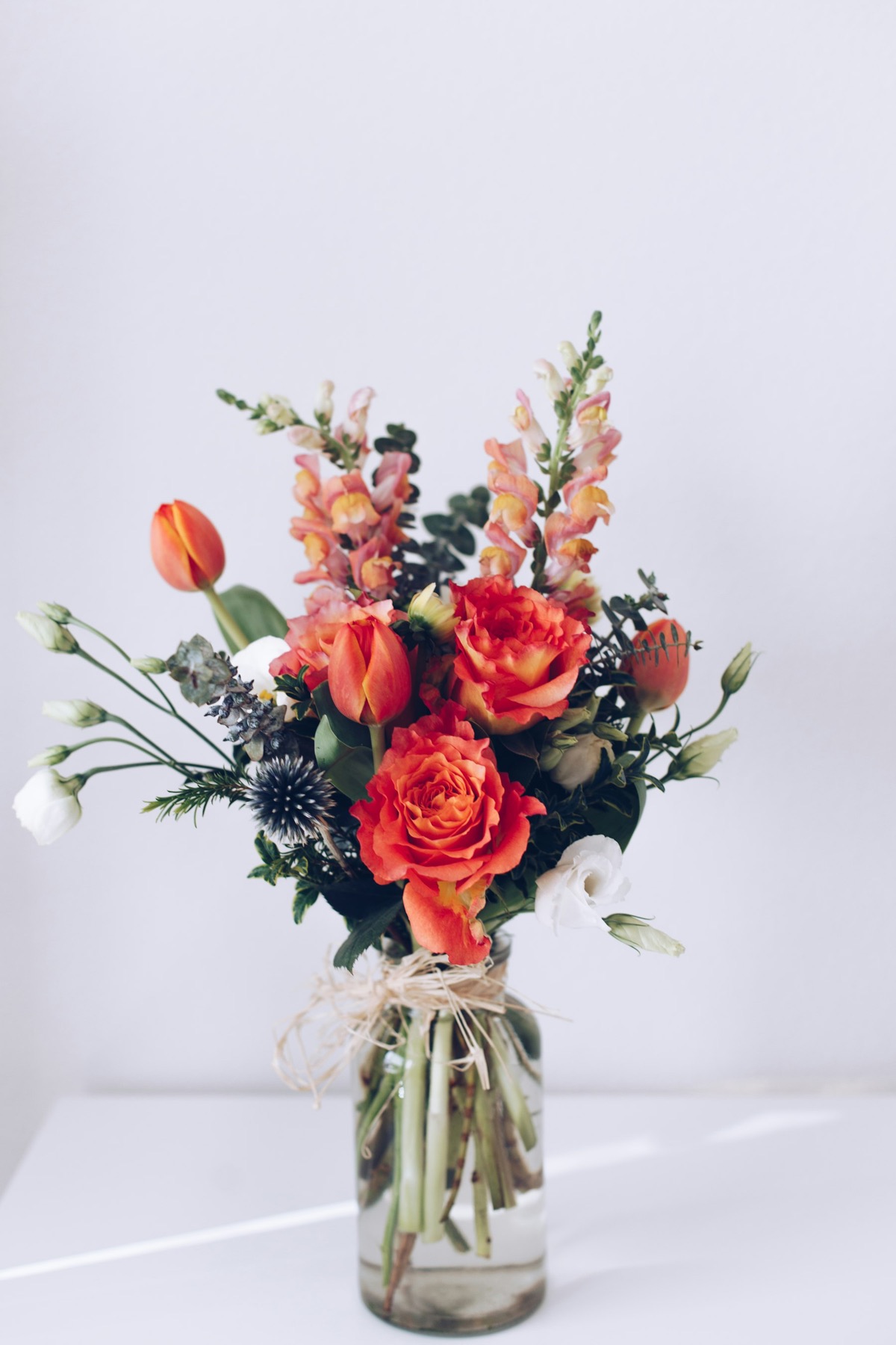 Snapdragon, coral roses and thistle — made to sit low on a table.