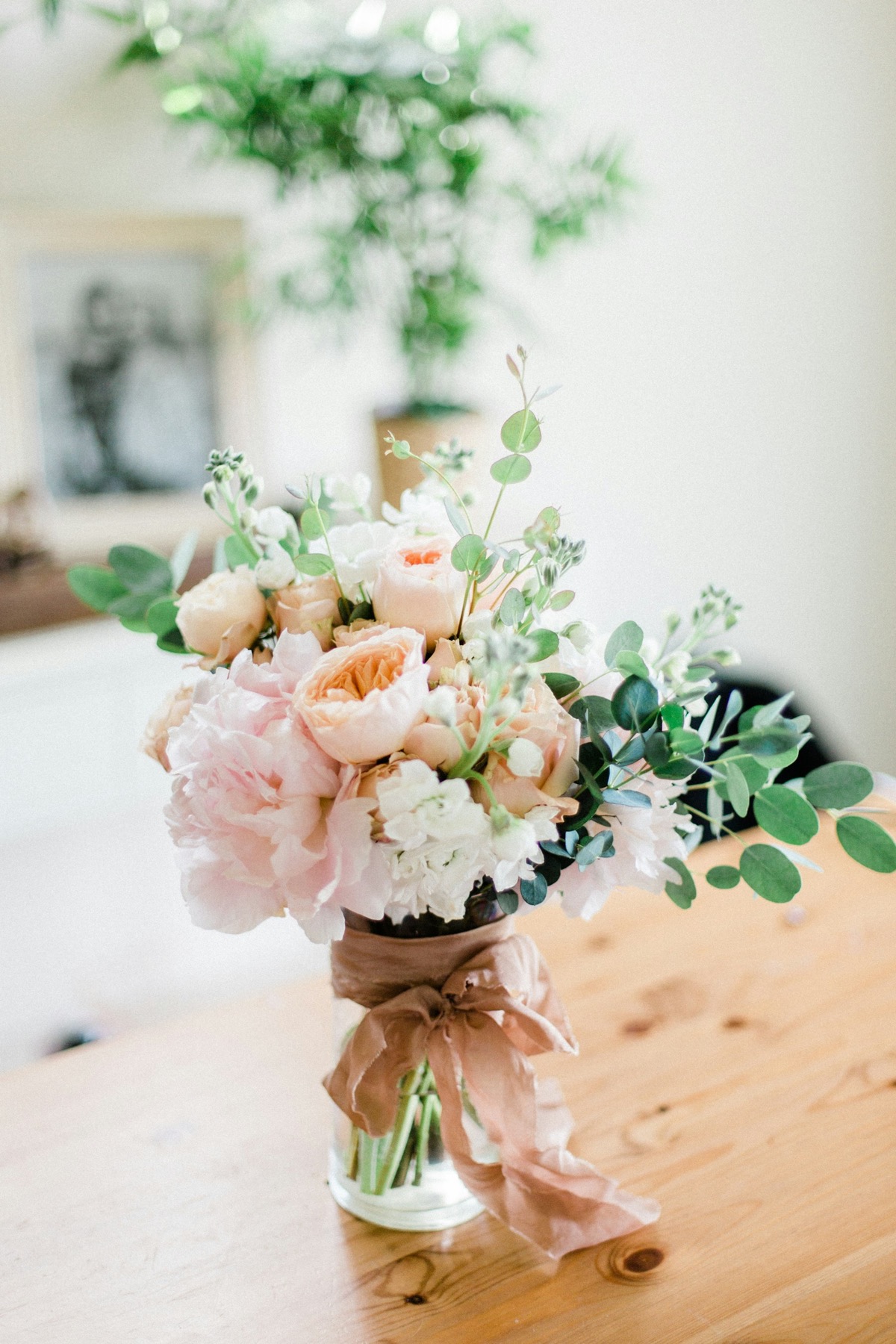 Blush peonies and cream spray roses loosely set in a clear jar.