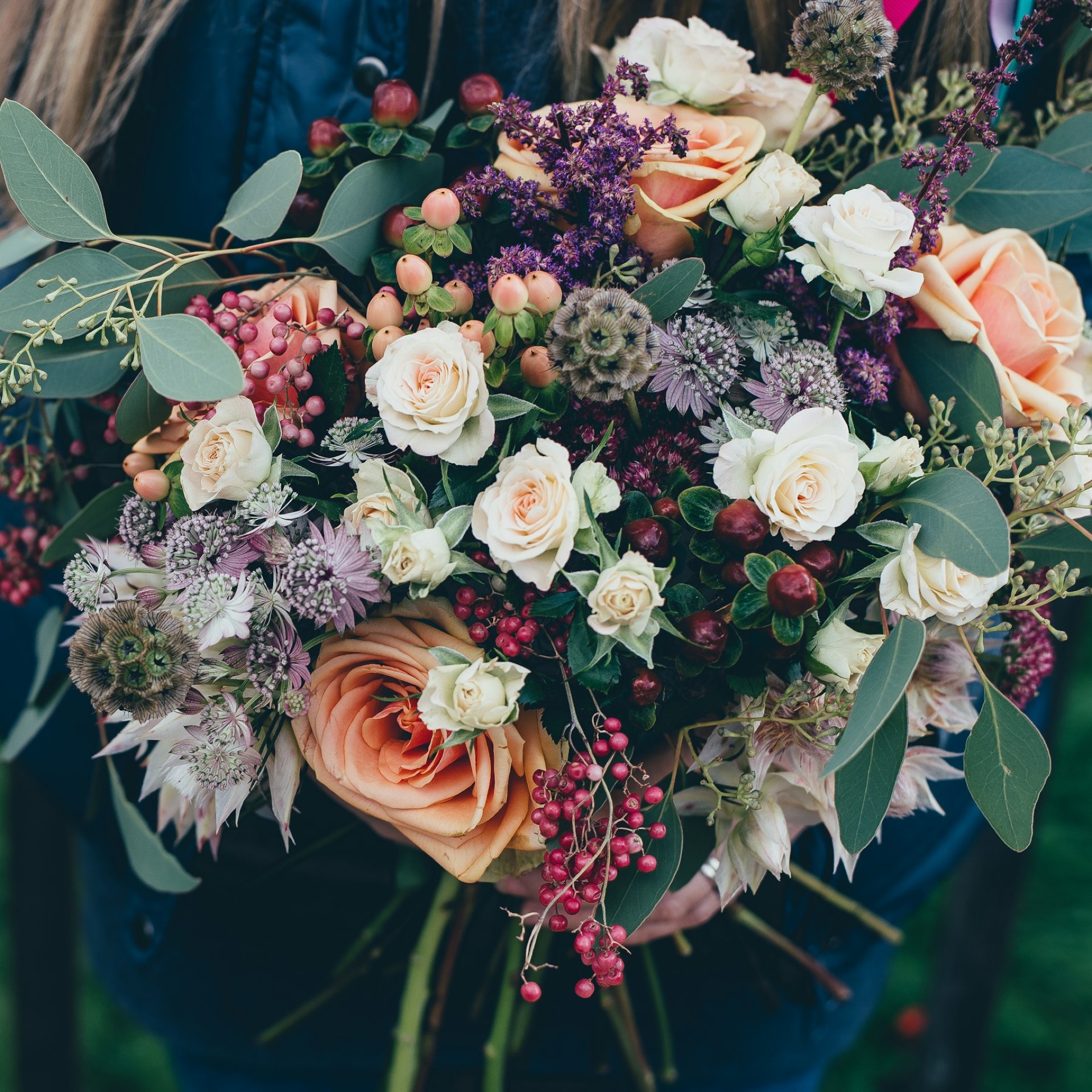 A lush hand-tied bouquet of cream roses, blush garden roses and seasonal stems