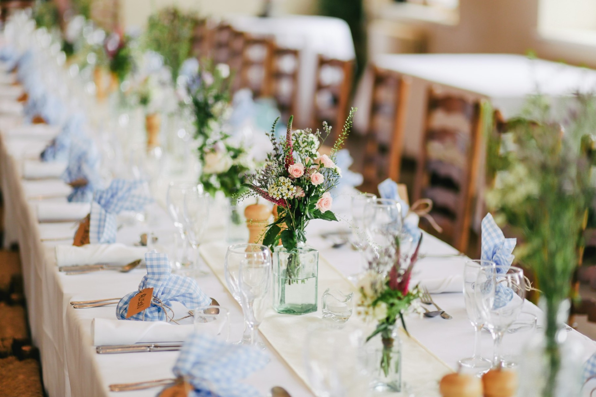 A long wedding reception table set with small vases of wildflowers